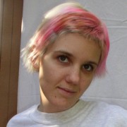 Young woman with short blonde hair and pink highlights